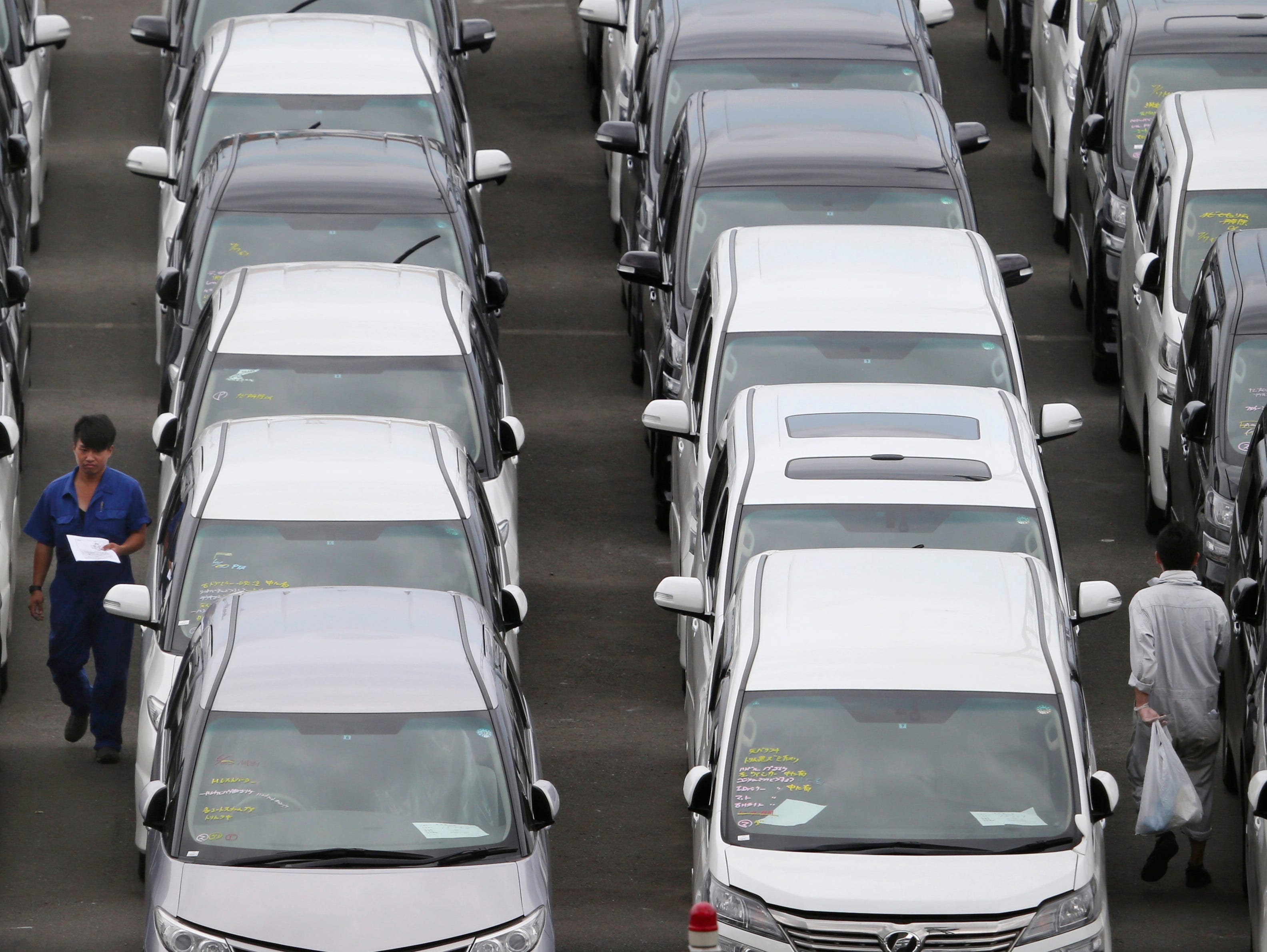 A  man, left, checks Toyota cars parked before being loaded onto a cargo ship in this 2014 file photo