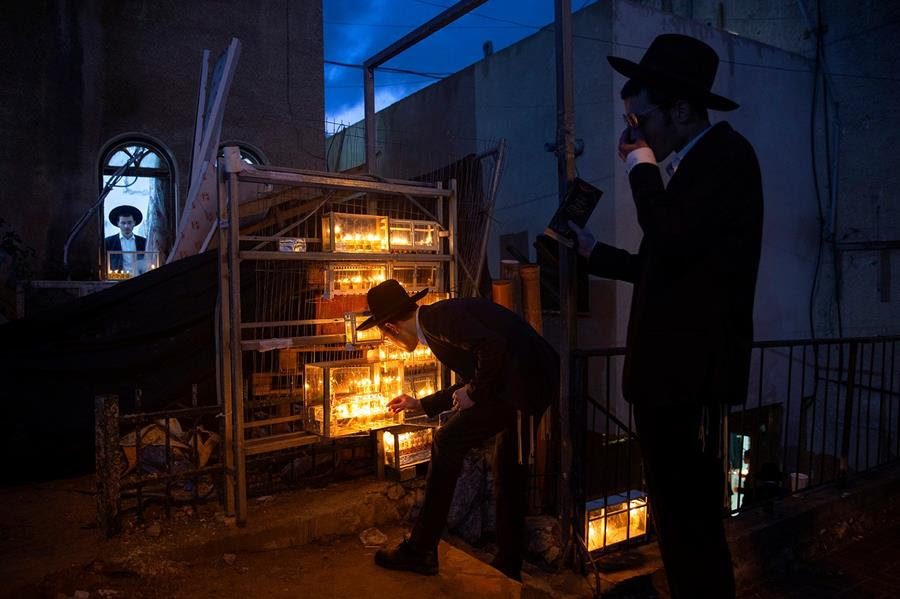 Ultra-Orthodox Jewish yeshiva students light candles on the fourth day of the Jewish holiday of Hanukkah in the ultra-Orthodox city of Bnei Brak near Tel Aviv, Israel, Wednesday, Dec. 1, 2021.