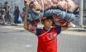 Un niño carga sus mantas hacia un refugio temporal en Gaza.