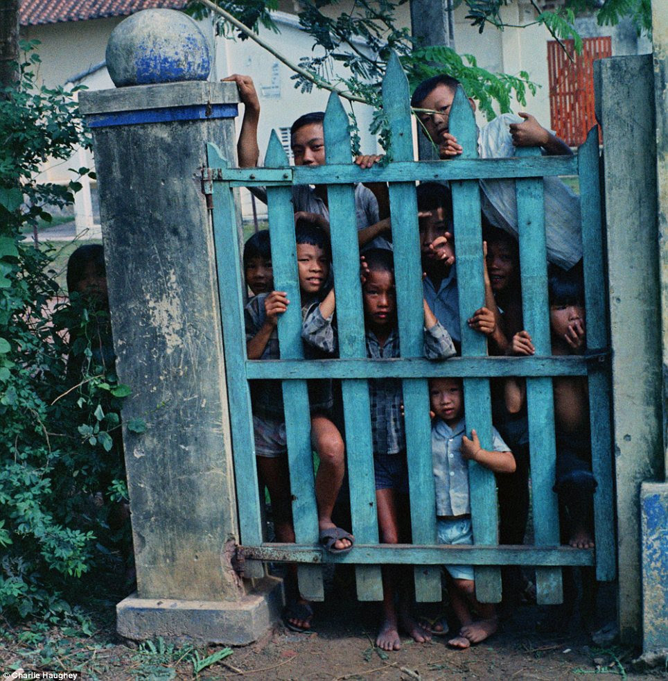 Locals: Vietnamese children peer through a gate at the American photographer during his tour in 1968-9