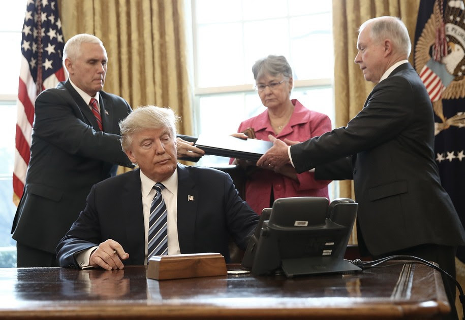 WASHINGTON, DC - FEBRUARY 09:  U.S. Vice President Mike Pence (L) hands three executive orders to newly sworn in Attorney General Jeff Sessions (R) for U.S. President Donald Trump to sign in the Oval Office of the White House February 9, 2017 in Washington, DC. Prior to signing the three executive orders, Trump participated in the swearing in ceremony for Sessions. Also pictured is Session's wife Mary (2nd R) (Photo by Win McNamee/Getty Images)