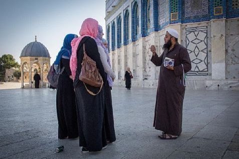 Muslim man speaking with a group of women at the Dome of the Rock mosque on the Temple Mount.