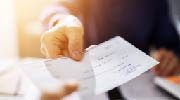 Close-up of a person handing a check to another person.  