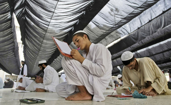 Các sinh viên Pakistan ngồi trên sàn nhà để làm bài thi hàng năm tại chủng viện Hồi giáo   Jamia Binoria ở Karachi, Pakistan vào ngày 8/6/2013. Ảnh: Fareed Khan/AP.
