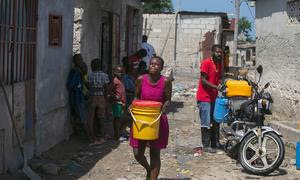 Una mujer de Puerto Príncipe (Haití) transporta agua que ha comprado a un comerciante local.