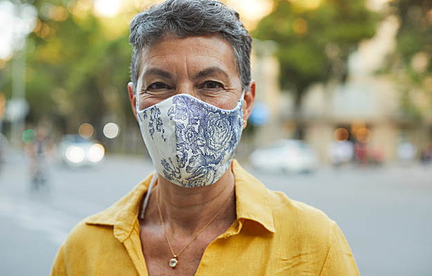 A mature woman wearing a cloth face mask outside.