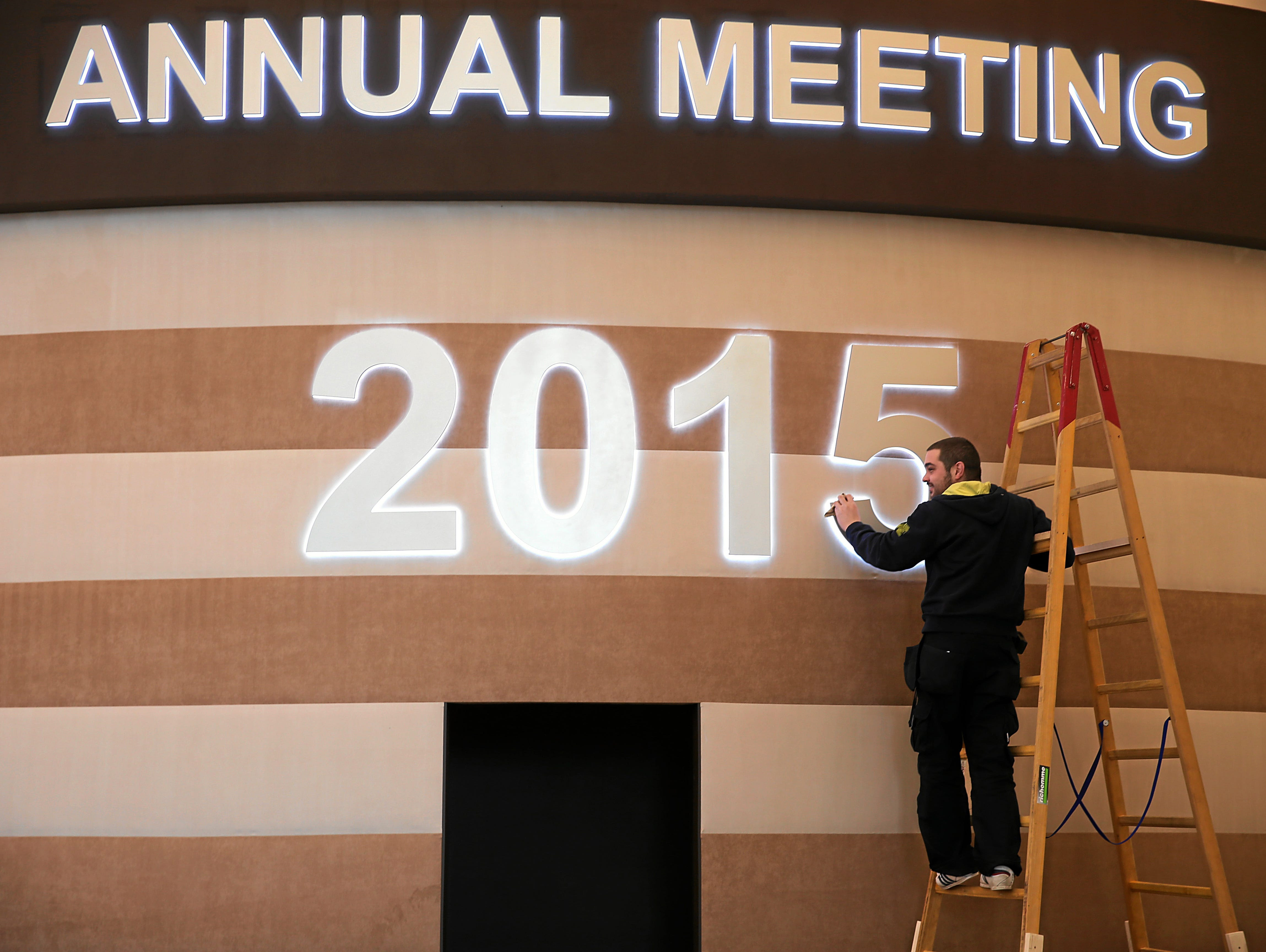 A worker cleans the neon sign at the venue of the 2015 annual meeting of the World Economic Forum in Davos.