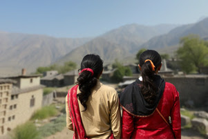 Two women are on a path in a village.
