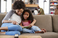 African American Mother and Daughter Reading on the Couch