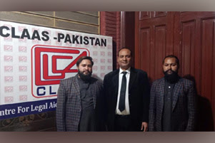 Raja and Rocky are standing with their attorney. A banner for CLAAS (Center for Legal Aid Assistance & Settlement) is on the wall behind them.