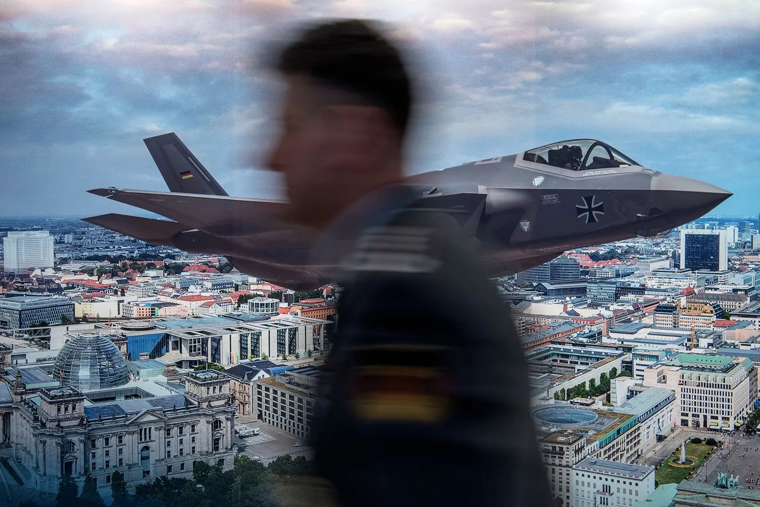 An unidentified participant walks past a poster advertising U.S. defense manufacturer Lockheed Martin’s F-35 stealth fighter over a Berlin skyline at the Berlin Security Conference in Berlin on Nov. 29, 2017.