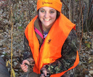 a young hunter holding a deer she harvested