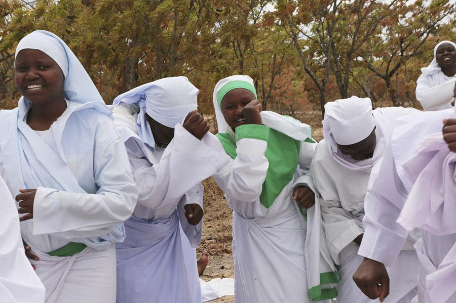 Members of an Apostolic Christian Church group gather for a prayer meeting. They are wearing light colored garments.