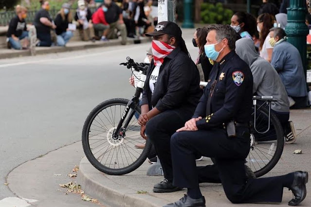 Polisi di Santa Cruz berlutut di tengah demonstran, sebagai bentuk dukungan atas protes kematian George Floyd. Foto ini diunggah Twitter @SantaCruzPolice pada Minggu (31/5/2020).(Twitter @SantaCruzPolice)