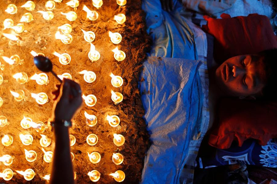 A man lies still as devotees light oil lamps over his body as part of rituals to celebrate the tenth and final day of Dashain festival in Bhaktapur, Nepal, Friday, Oct. 15, 2021. The festival commemorates the slaying of a demon king by Hindu goddess Durga, marking the victory of good over evil. (AP Photo/Niranjan Shrestha)