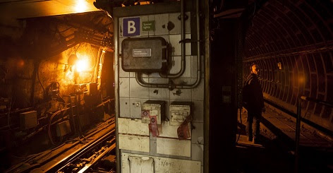 A divider between two underground train tunnels, lit with warm orange light