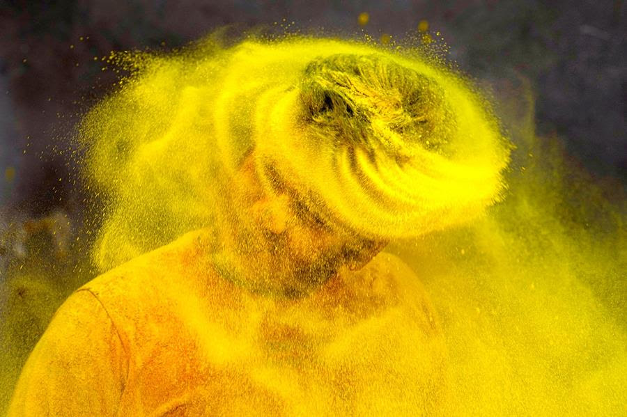A man whips yellow powder out of his hair while celebrating Holi, the Hindu festival of colors.