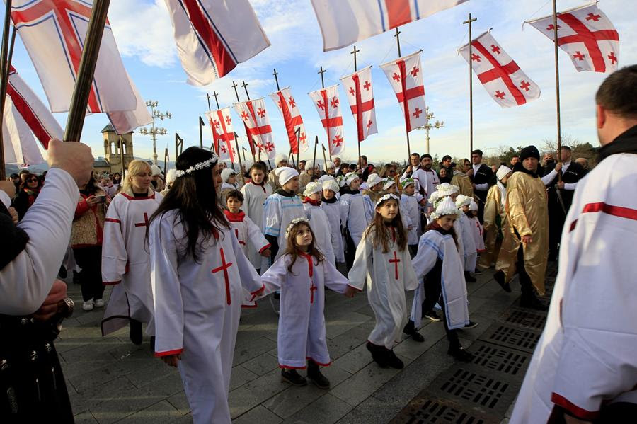 Georgian families carry national flags as part of a procession to mark Orthodox Christmas.