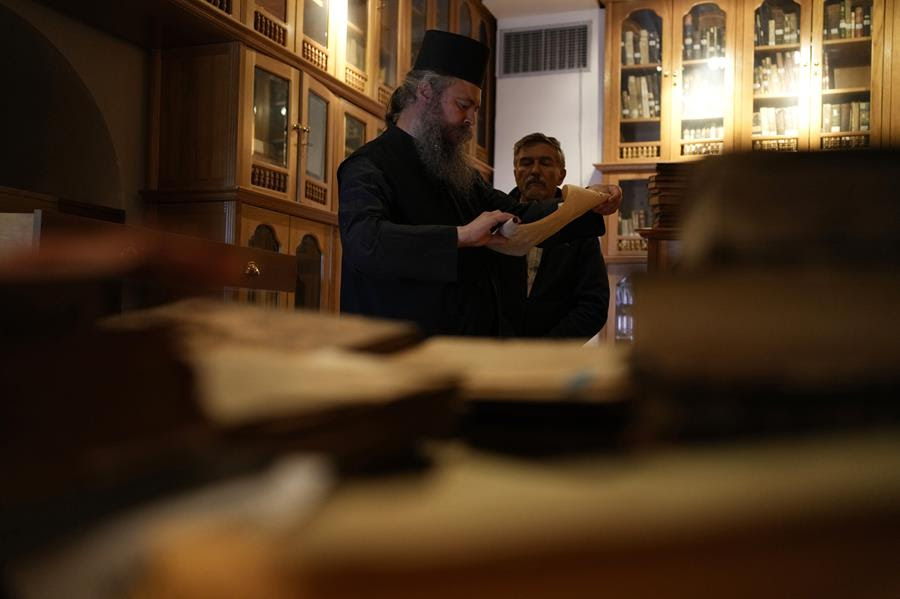 Father Theofilos, a Pantokrator monk reads a manuscript as Anastasios Nikopoulos, a jurist and scientific collaborator of the Free University of Berlin, looks on at the library of Pantokrator Monastery in the Mount Athos.