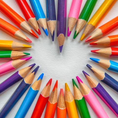 Different coloured pencil crayons creating the shape of a heart