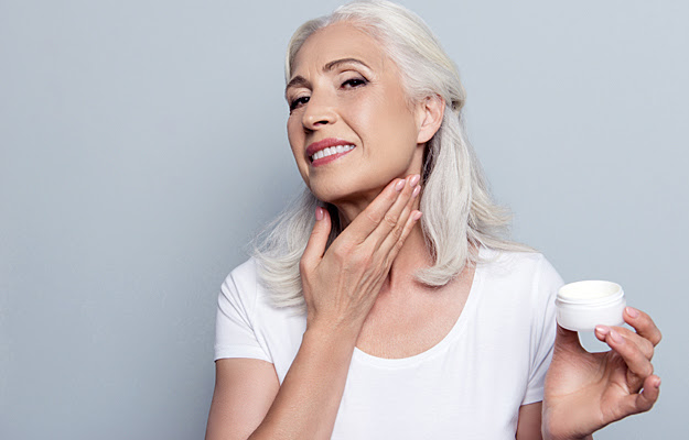 A mature woman moisturizing her neck.