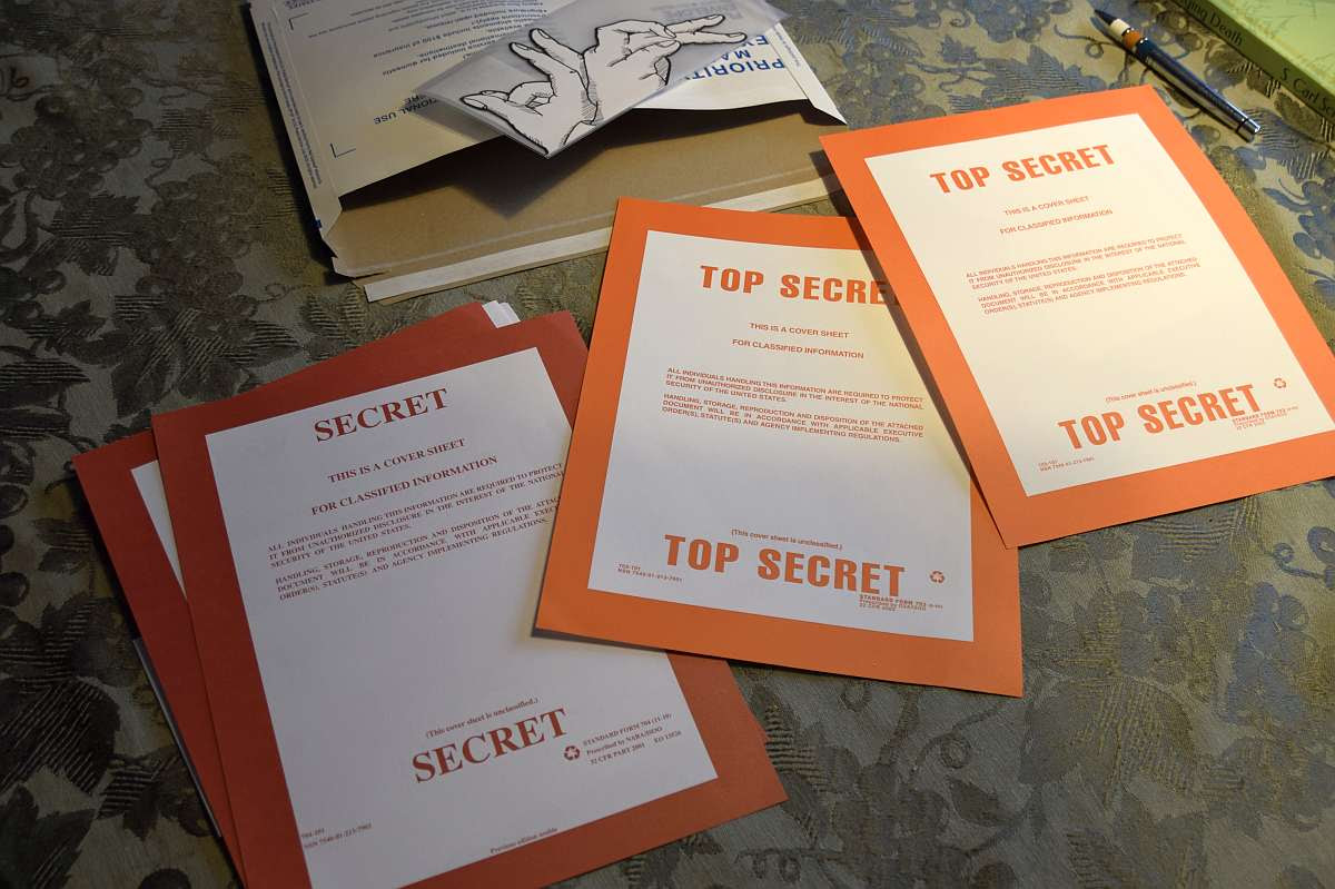 Table covered with sheets that say "Top Secret" or "Secret."