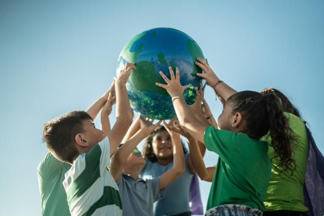 a diverse group of children playing outside holding a globe