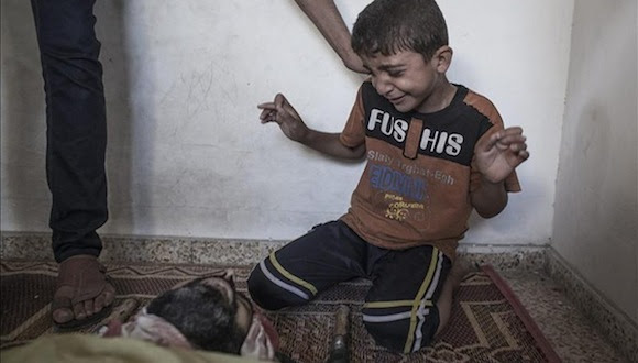 Foto: Un niño llora junto al cadáver de un familiar muerto en el ataque a la escuela de la ONU. Foto: Oliver Weiken/EPA.