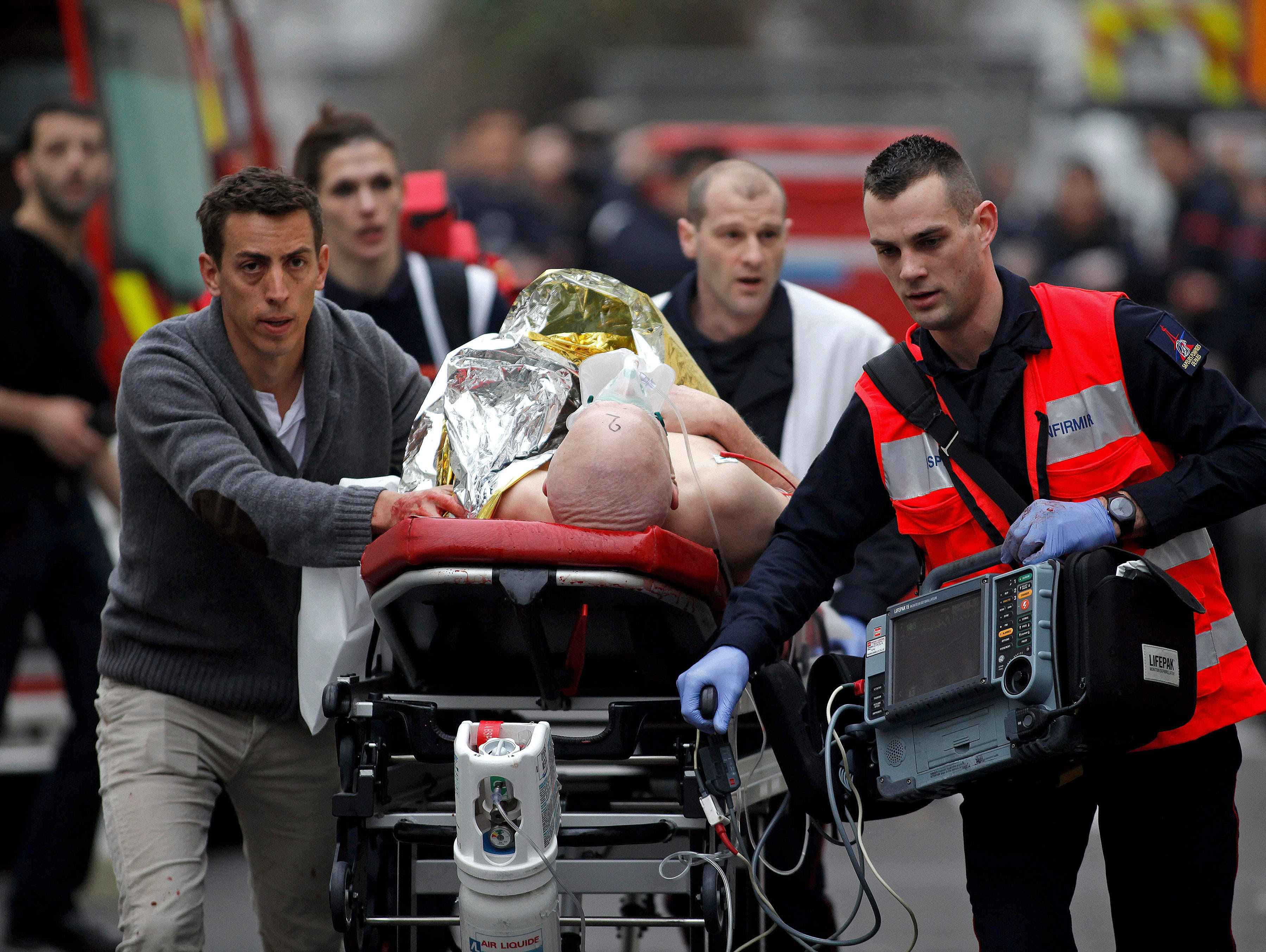 An injured person is evacuated outside the office of the satirical newspaper 