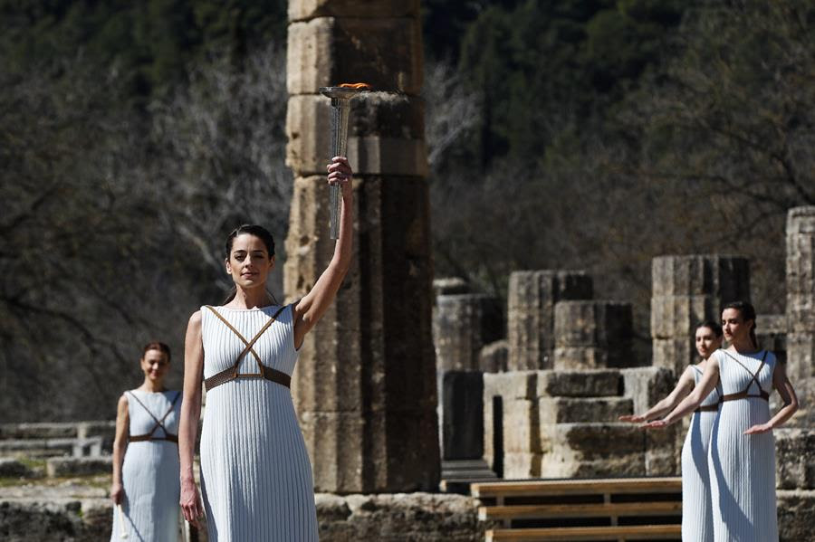 Greek actress Xanthi Georgiou, playing the role of the High Priestess, holds up the torch during the flame lighting ceremony at the closed Ancient Olympia site, birthplace of the ancient Olympics in southern Greece, Thursday, March 12, 2020.