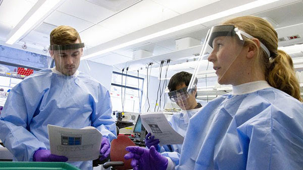 Michelle Cipicchio pictured with two lab technicians wearing protective face shields