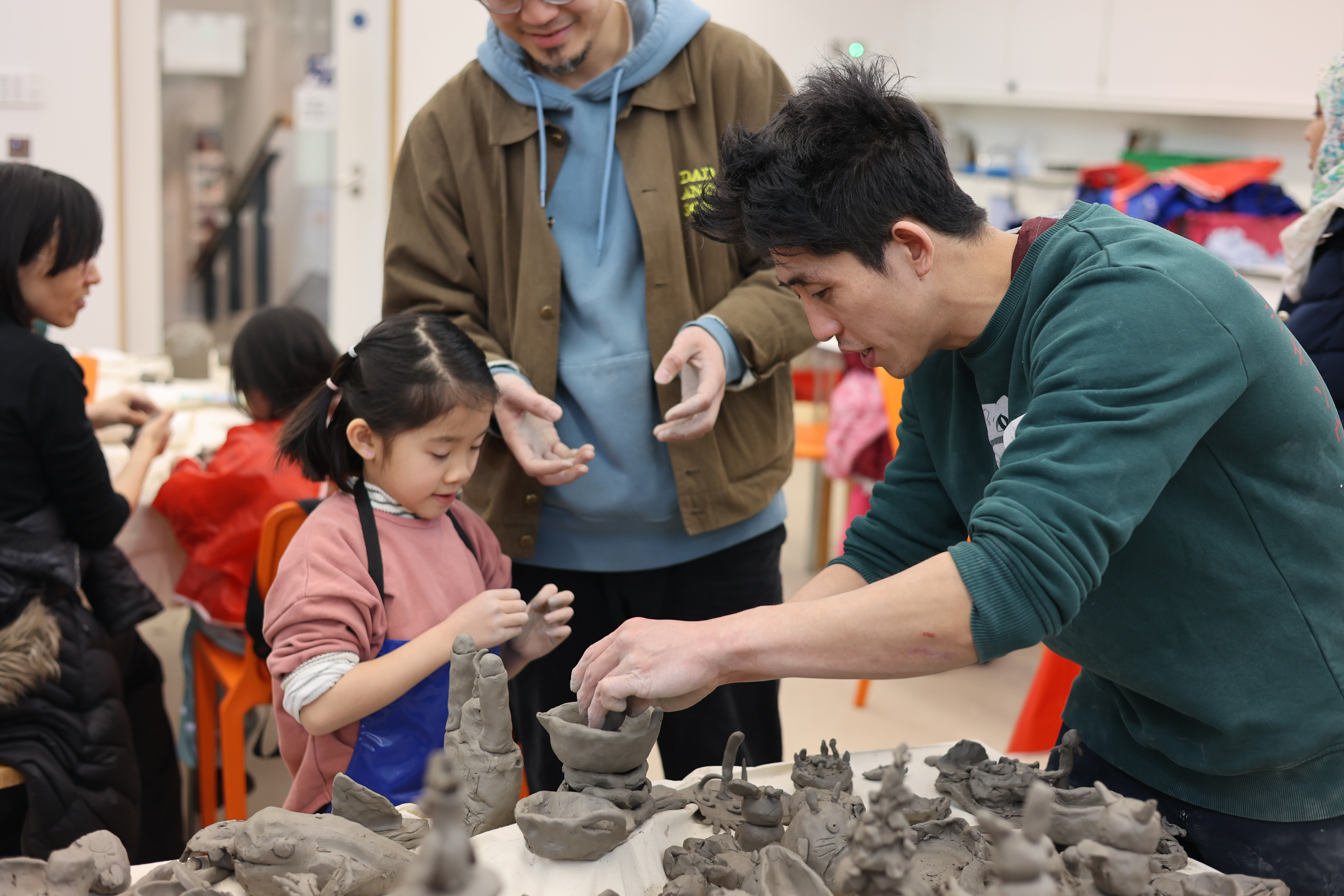 A child and an adult building with clay