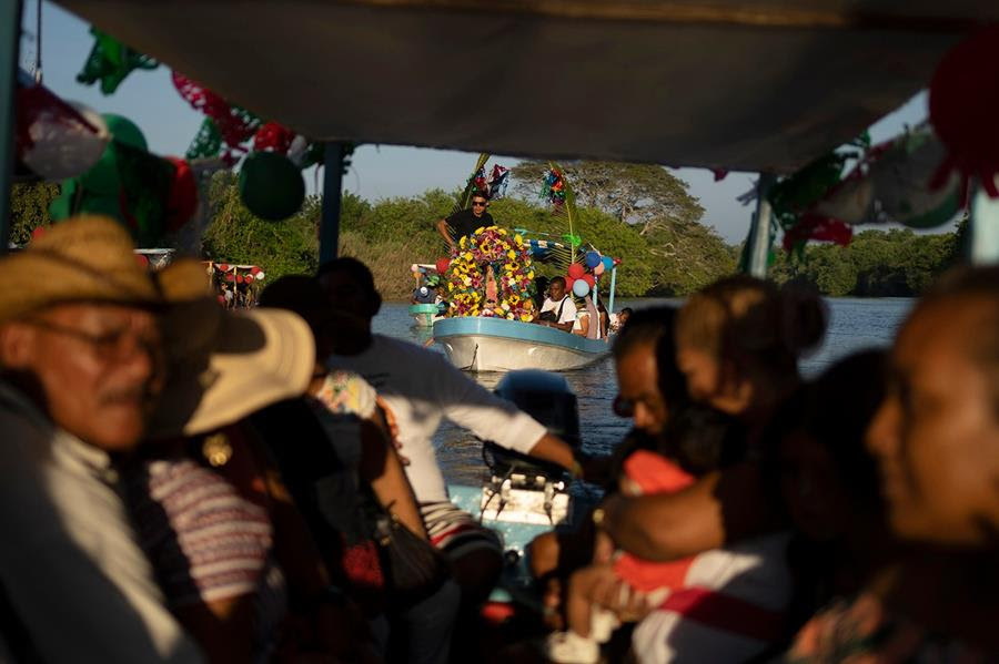 Villagers ride on boats during a celebration to honor the Virgin of Guadalupe. The boats are decorated with bright flowers.