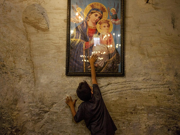 Picture of a young boy reaching to touch a painting of Mary