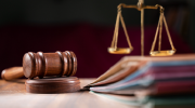 Symbols of justice: a gavel, scales and several file folders on a desk. 