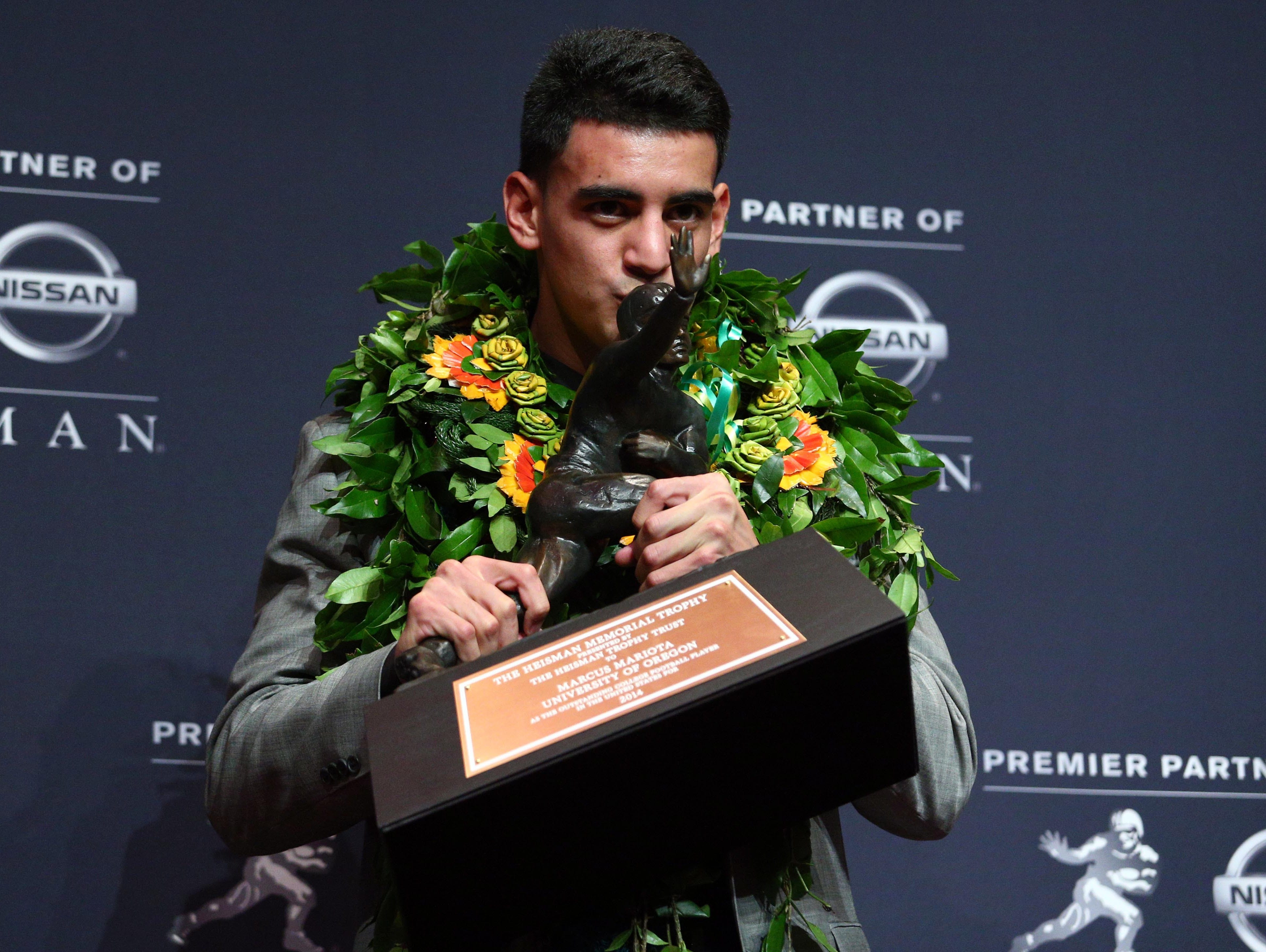 Dec 13, 2014; New  York, NY, USA; Oregon Ducks quarterback Marcus Mariota kisses the Heisman Trophy during a press conference at the New York Marriott Marquis after winning the Heisman Trophy. Mandatory Credit: Brad Penner-USA TODAY Sports