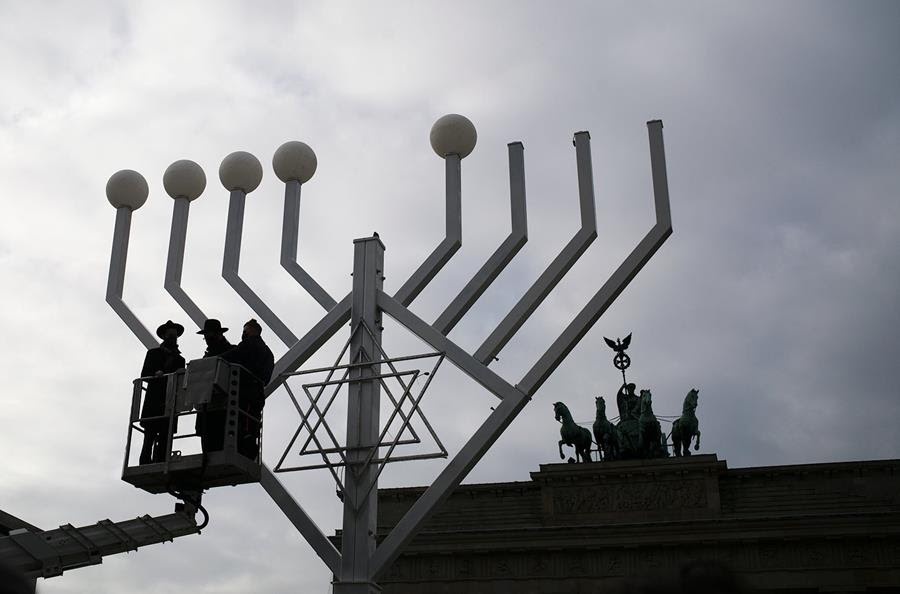 Rabbi Segal Shmoel, from left, and Rabbi Yehuda Teichtal inspect a giant Hanukkah Menorah, set up by the Jewish Chabad Educational Center, ahead of the Jewish Hanukkah holiday, at the Pariser Platz in Berlin, Germany, Friday, Nov. 26, 2021. (AP Photo/Markus Schreiber)