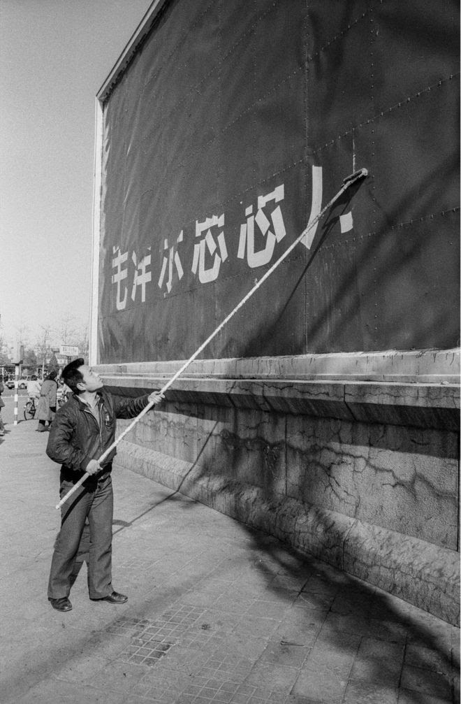 A man paints over a billboard