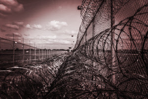A prison fence with rows of rolled barbed wire