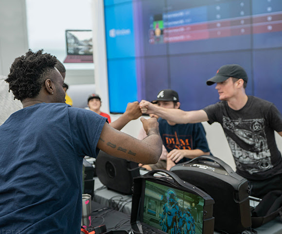 Gamers greeting each other with fist bumps as they compete in store.