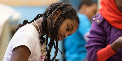 Young Black student's head bent down as she writes