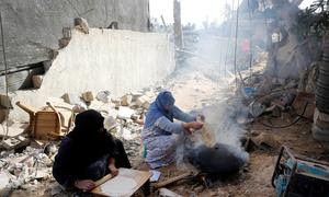 Unas mujeres hornean pan rodeadas de edificios destruidos en Jan Yunis, Gaza, durante la reciente pausa humanitaria.