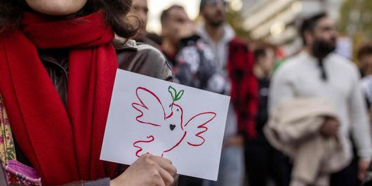 A demonstrator displays a card with a dove of peace during a rally in solidarity with the Palestinians in the Gaza Strip in Warsaw, Poland on October 29, 2023. Thousands of civilians, both Palestinians and Israelis, have died since October 7, 2023, after Palestinian Hamas militants based in the Gaza Strip entered southern Israel in an unprecedented attack triggering a war declared by Israel on Hamas with retaliatory bombings on Gaza. (Photo by Wojtek RADWANSKI / AFP)