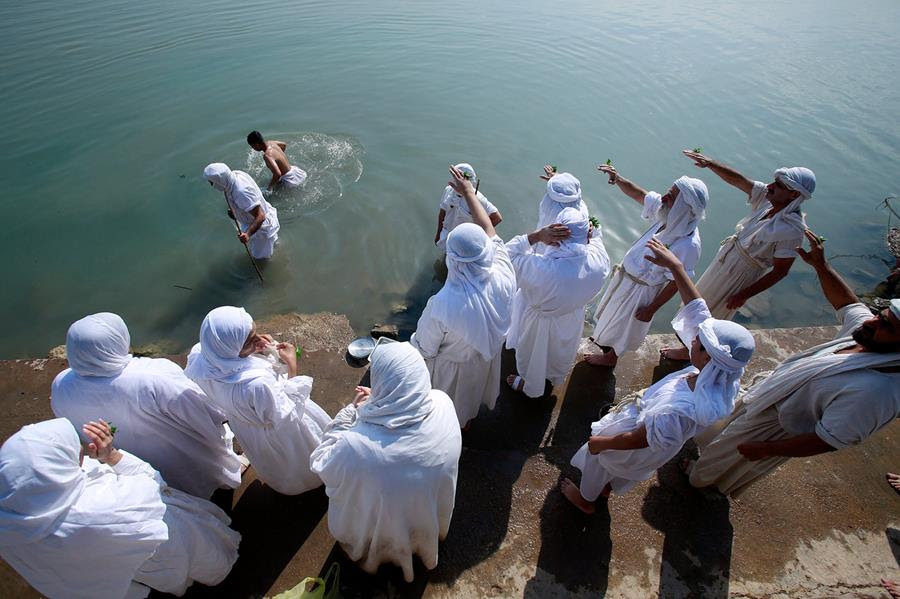 Followers of the ancient Sabean Mandaean religious sect pray alongside the Tigris river during the Prosperity Day celebration. They are wearing white clothing.