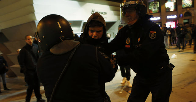 Dos agentes antidisturbios agarran a un manifestante en apoyo a Gamonal en la Plaza de Callao de Madrid.