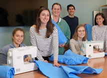 staff gather near sewing machine