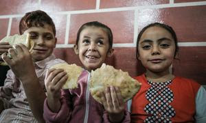 Niños refugiados en una escuela de UNRWA en Gaza disfrutan del pan distribuido por el PMA.