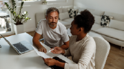 A man and woman review financial documents at the table. 