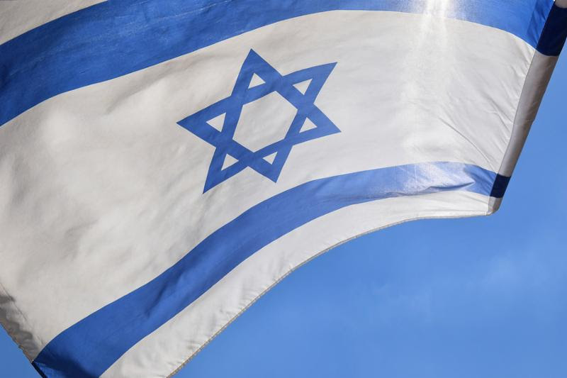 Star of David on a blue and white israeli flag against a bright sky