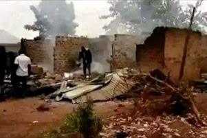 Two men walking through the burned remains of buildings.